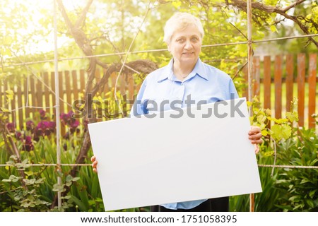 elderly woman holding a blank vertical canvas in her hands. Empty frame for text or photo. woman with mockup poster