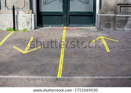 Entrance to a pub with yellow sticker tape reminding people in Dutch to keep social distancing 1,5 meter and in which direction to enter and exit the pub, due to Coronavirus disease (COVID-19)