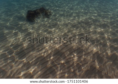 Underwater seabed of sand and rocks with reflections of the sun on the water. Mediteranea sea
