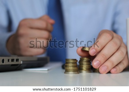 Save money with stack money coin for growing your business concept.Concept of enrichment and financial growth. Gold coins. Hand add coin to stack, saving money. Income Tax Raise. 