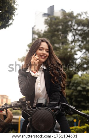 woman riding her cafe racer type motorcycle. using the cell phone. beautiful latina