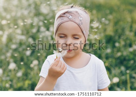 The girl blew on a dandelion, closed her eyes and dandelion seeds fly around her