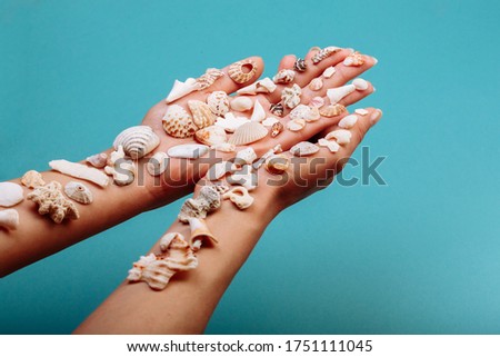 Macro of hand holding different kinds of seashells, corals in front of a blue background, isolated with a caption for text. Vacation concept