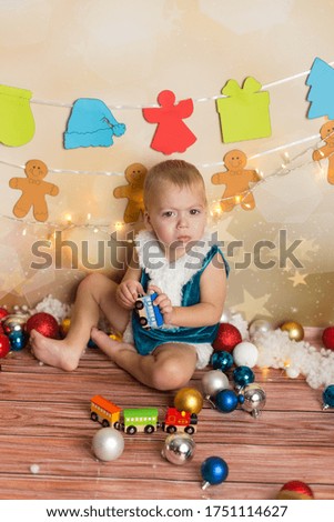 a little boy in a blue Christmas suit. a boy plays with a toy train