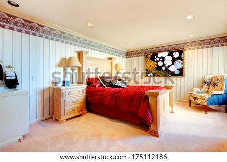 Ivory bedroom with carved queen size bed and night stand, red bedding and floral antique chair