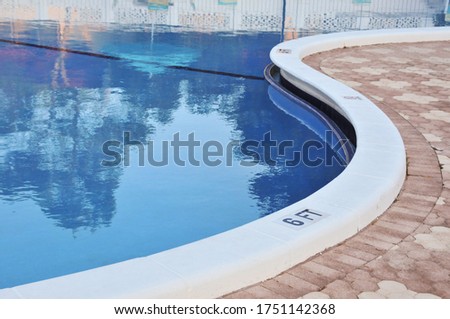 An inground swimming pool with the deck undulating in an "s" shape. Royalty-Free Stock Photo #1751142368