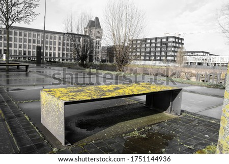 Urban development whose nature takes over these rights by lichens on the benches. Winter photo with rehabilitated industrial buildings in the background. 