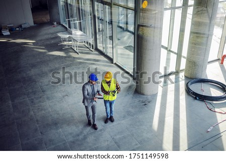 Top view of contractor and architect walking around building in construction process and talking about how they gonna build it. Royalty-Free Stock Photo #1751149598