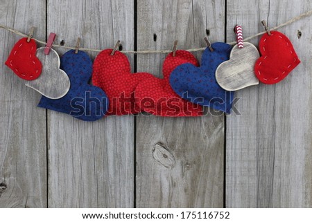 Red, blue and wood hearts hanging on clothesline with old weathered wood background