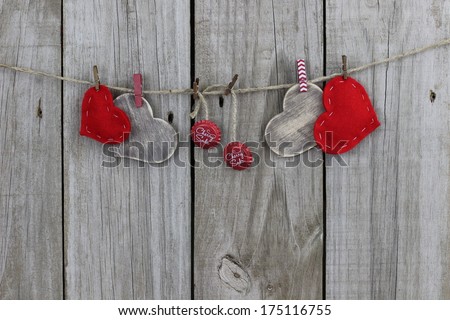 Red hearts, wood hearts and cherry soda bottle caps hanging on clothesline with rustic antique wood background; Valentine's Day, Christmas and love concept with copy space
