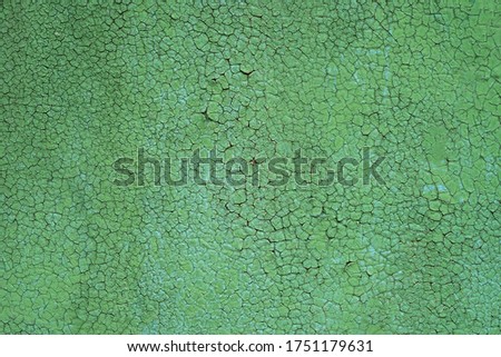 Old cracked green paint background. Closeup texture of old paint on a metal surface. Many cracks from dried paint.