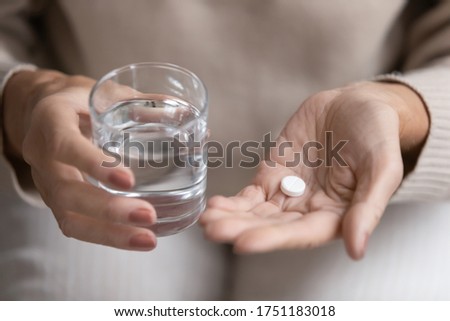 Close up top view of older woman hold glass of water and antibiotic aspirin pill feel unhealthy at home, sick mature female take daily dose of supplements or vitamins, elderly healthcare concept Royalty-Free Stock Photo #1751183018