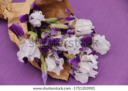 White irises with purple petals in brown сraft paper on a purple background.