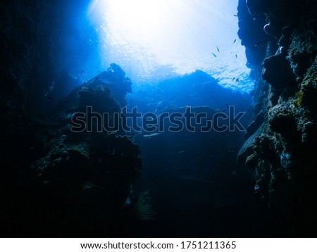 Underwater Background - Blue Water Backdrop. Aqua Marine Abstract Nature. Looking up to chimney light source shading onto Giant Rocky Slope Wall. Environment ambient under Indo Pacific - Indian Ocean.