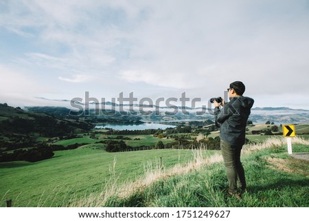 Asian tourist man photographer with camera taking pictures in mountains on foggy weather day.