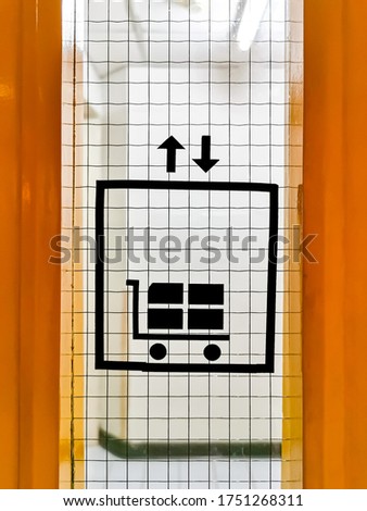 Freight elevator (or lift for goods) sign installed on wired glass panel of yellow metal doorway for service lift area in hi-rise office building.