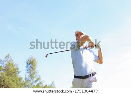 Golfer hitting golf shot with club on course while on summer vacation.