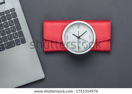 Time to make money.Online business. White clock, laptop and red wallet on gray background. Minimalistic studio shot. Top view