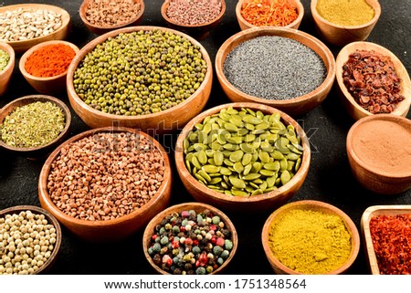 Top view of different kinds of colorful spices in wooden bowls on black stone surface. Flat view of spice kinds.