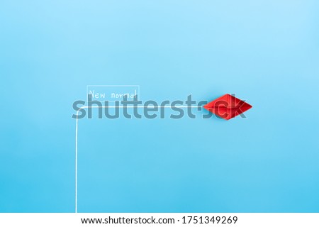 red paper ship in new direction on blue background, New normal concept, copy space 