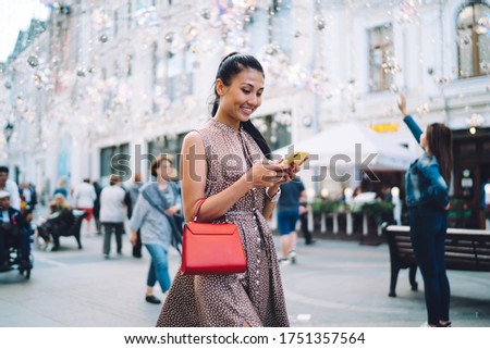 Happy Asian woman with digital smartphone technology chatting while walking in touristic city enjoying summer vacations for travelling, cheerful millennial girl with cellphone writing email message