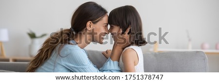 Horizontal photo banner for website header design loving mother seated on couch touching noses face with adorable little daughter. Happy motherhood, cherish, family bond and unconditional love concept
