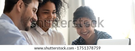 Three multi ethnic colleagues involved in learning new corporate business application seated together in coworking desk, teamwork mentoring concept. Horizontal photo banner for website header design Royalty-Free Stock Photo #1751378759