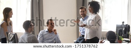 African team leader talking to colleagues at modern office during meeting. Employees listen speaker new ideas, goals at corporate briefing training. Horizontal photo banner for website header design