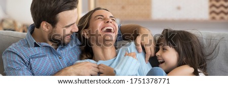 Laughing husband and daughter tickling mother family play together having fun resting on sofa at home close up photo. Weekend activities, affection concept. Horizontal banner for website header design