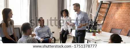 Multi ethnic corporate staff listen team leader company boss during morning briefing in coworking open space office. Mentoring, brainstorming concept. Horizontal photo banner for website header design