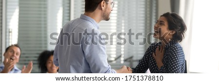 Diverse businesspeople shake hands standing in office. Company boss congratulate indian female employee with reward, promotion, career growth concept. Horizontal photo banner for website header design