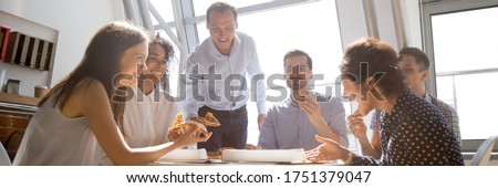 Group of multiethnic colleagues friends gathered together eating pizza talking and laughing during lunch break. Teambuilding, corporate party concept. Horizontal photo banner for website header design
