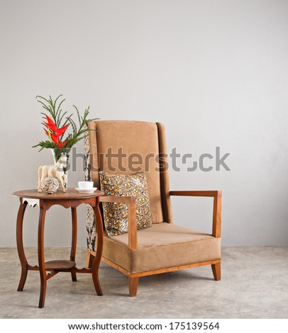 Beige upholstered chair with side table and flowers