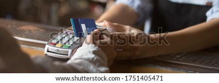 Customer stand near bar counter make payment use contactless credit card close up hands device view, cashless method pay bills in commercial places concept. Horizontal banner for website header design