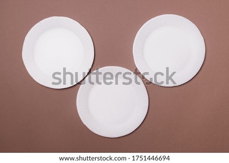 three eco-friendly white cardboard plates in form of mouse lie on brown background. Top view. Close-up.