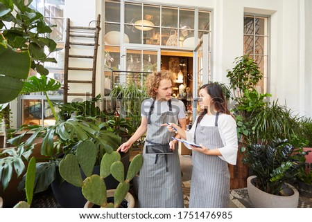 Florist team with tablet computer taking inventory between green plants