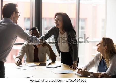 Middle-aged asian korean ethnicity businesswoman shake hands with european millennial client. In modern board room group meeting team leaders greeting each other handshaking showing trust and respect Royalty-Free Stock Photo #1751484302