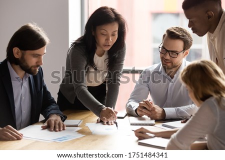 Five diverse business workgroup designers team with asian woman leader discuss paperwork financial report statistical data, forecasting working on common project. Brainstorm, briefing activity concept Royalty-Free Stock Photo #1751484341