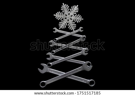 Abstract christmas tree made of wrenches with snowflate on the top on black background. Industrial christmas, winter, new year concept. Home decoration. Mechanic, handyman greeting card concept.