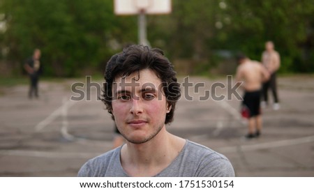 A young man with blush on cheeks posing at the basketball court after playing basketball