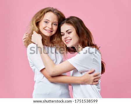 Mom and daughter hugs joy smile pink background