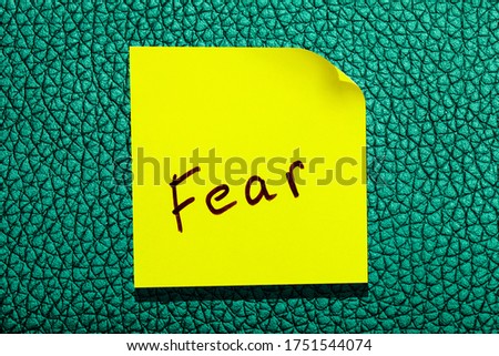 yellow sticky leaf on the wall. inscription marker word fear