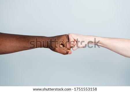 Closeup photo of two arms different race skin colors multinational friends antiracism issue help together buddies world globe integration giving fists bump isolated grey color background Royalty-Free Stock Photo #1751553158