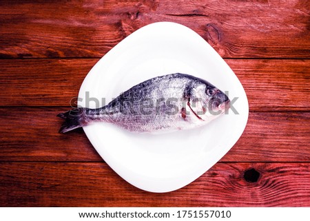 raw gold on a white plate and wooden table. Raw fish concept. View from above.