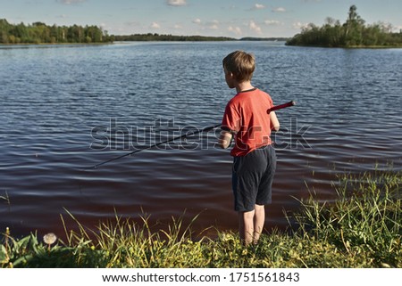 Children fishing on the shore of a large lake. Girls go fishing in the summer in the village.