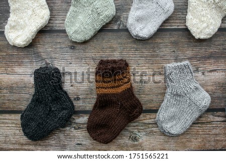 Various sizes and styles newborn baby socks on dark wooden background