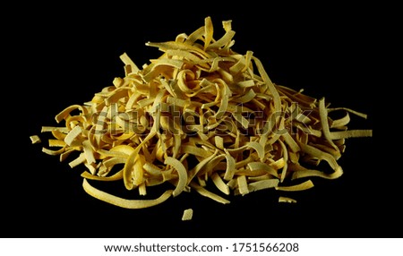 Raw tagliatelle pasta noodles with turmeric isolated on black background