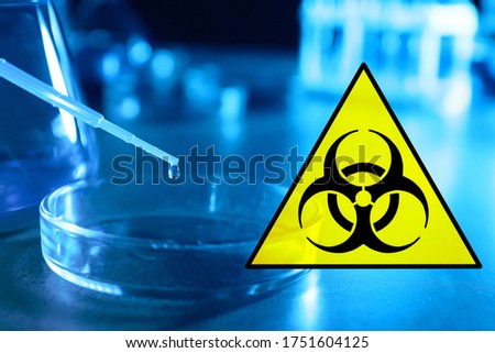 Poison sign and dripping liquid into Petri dish on table
