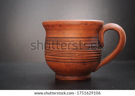 Clay cup against a dark background with the handle turned to the right