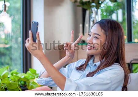 Beautiful and cute Asian women uses the phone to take a selfie. Women are happy and enjoy taking photos. The relaxation of a woman in ages 20-30 years